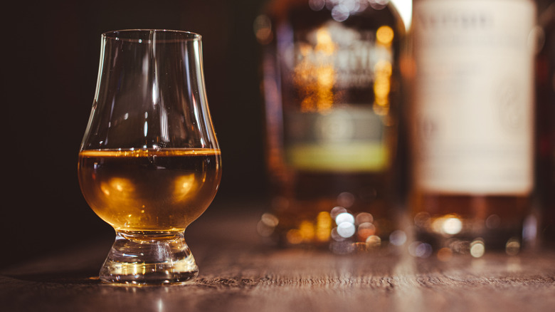 Scotch whisky in a Glencairn glass in front of blurred out bottles