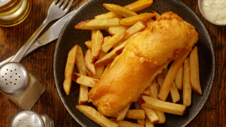Fish and chips on a grey plate next to cutlery