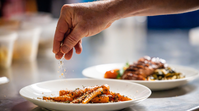 hand seasoning two plates of food