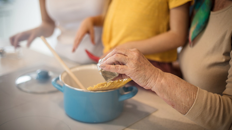 A grandma putting ingredients into blue bowl