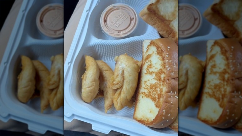 Naked chicken tenders in a styrofoam container with side sauce