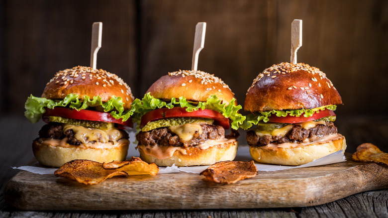 Three cheeseburgers on a wooden plate