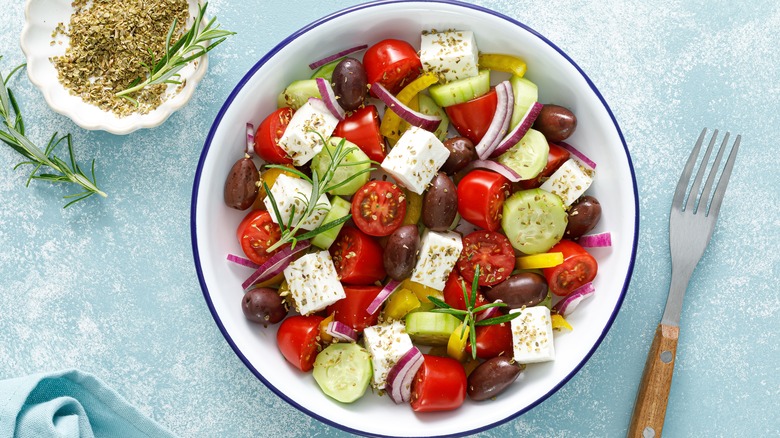 Bowl of Greek salad with fork and oregano