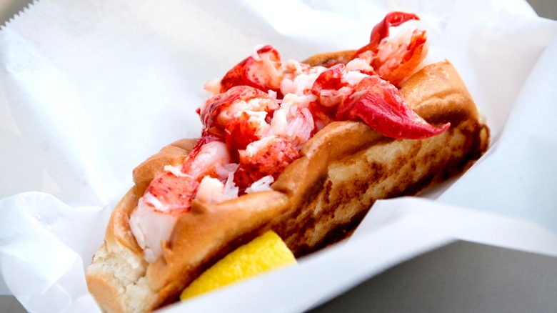 Lobster roll and lemon wedge from Cousins Maine Lobster sitting on wax paper