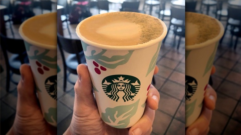 A person holding the Starbucks Juniper Latte up in a cup in a store