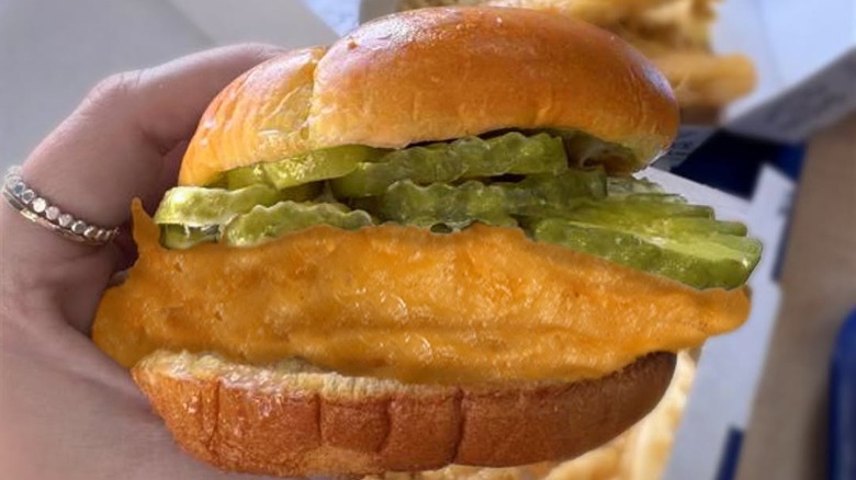 A close-up image of a woman holding a Long John Silver's fish sandwich