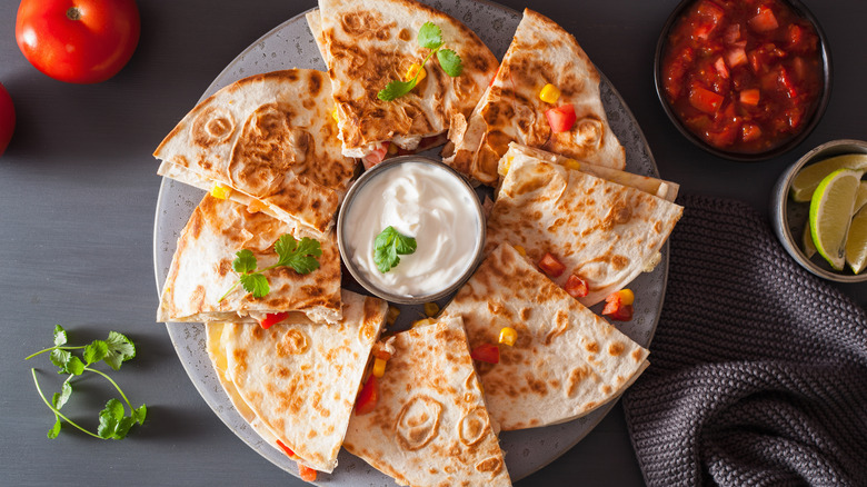 Quesadilla cut up on a plate with sour cream