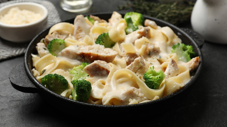 Small cast iron pan filled with pasta in creamy sauce with pieces of chicken and broccoli