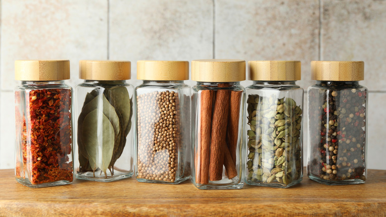 Glass spice jars with matching wooden lids filled with whole spices