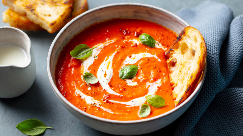 A bowl of tomato soup with cream and bread