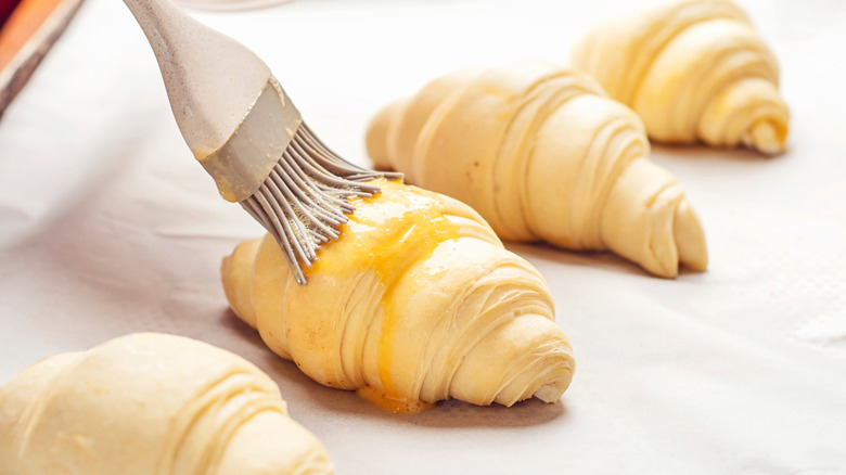 Croissants being brushed with egg wash