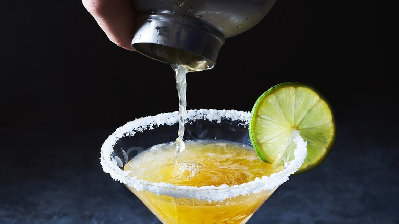 pouring margarita into salted rim glass