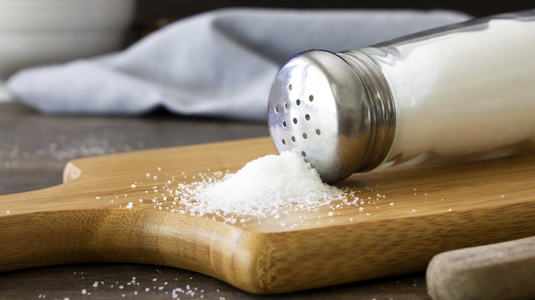 Salt shaker spilled over on a cutting board