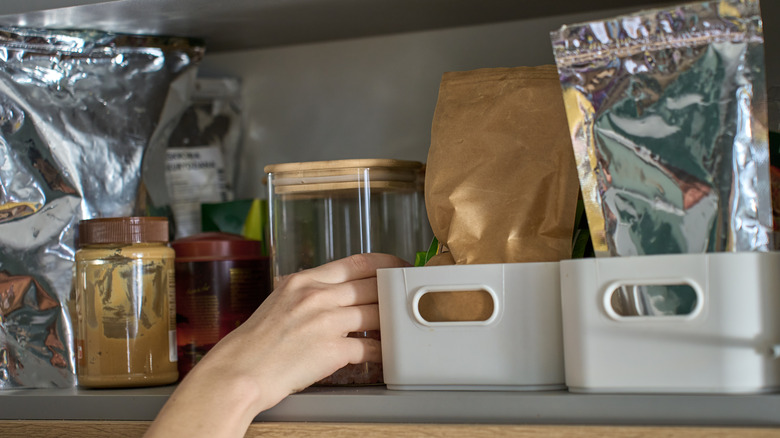 A person reaching into a well-organized pantry to get an item