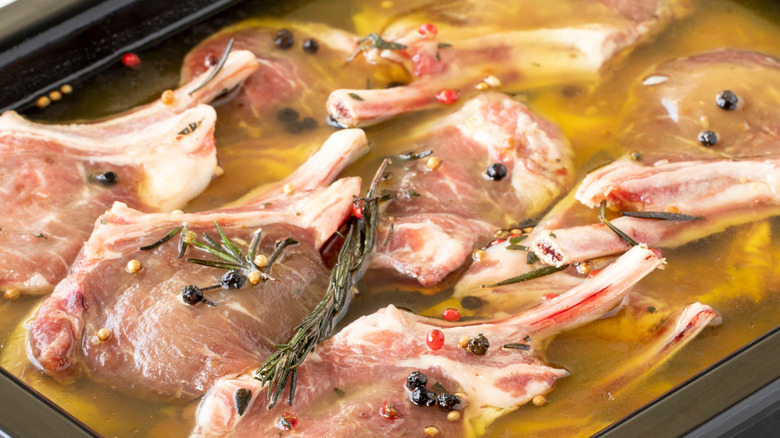 Lamb chops marinading in liquid with herbs and spices