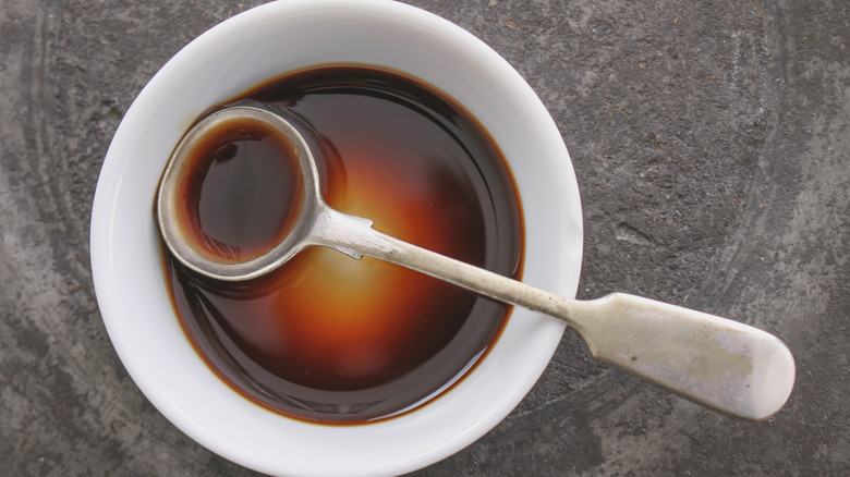 Worcestershire sauce in small white bowl with silver spoon