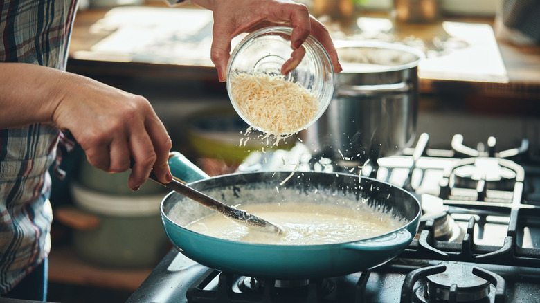 Preparing alfedo sauce in a blue saucepan