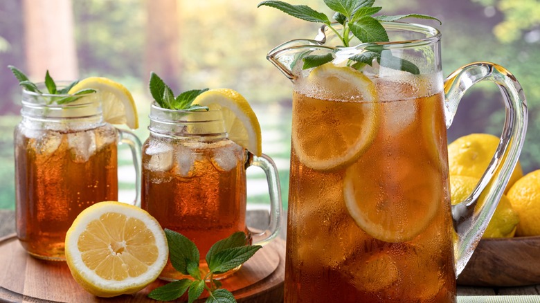 A pitcher and two glasses of iced tea with lemon slices