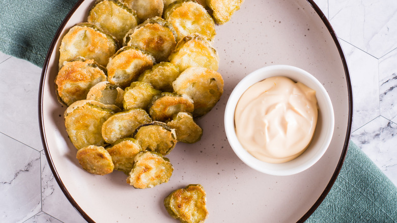 fried pickles on a plate with dipping sauce