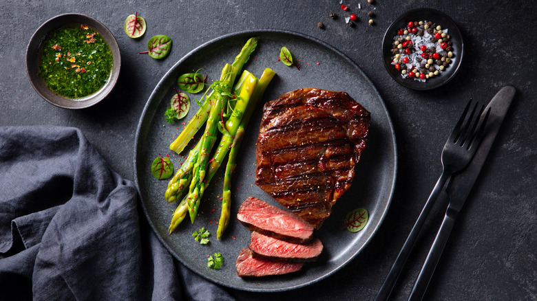 simple meal of steak and asparagus with chimmichurri sauce and salt and pepper