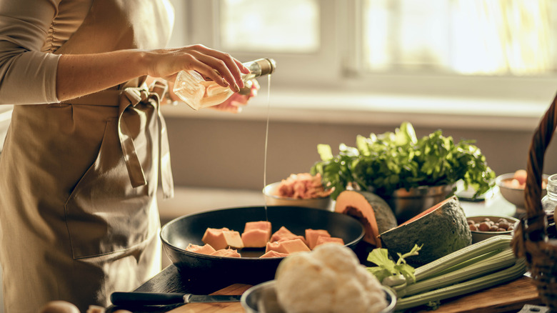 Woman pouring oil over pumpkin in a skillet