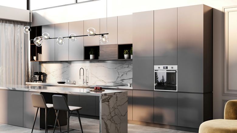 Kitchen with steel cabinets, marble island, and hanging lamps