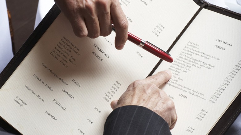 Close-up of hands pointing at items on a menu