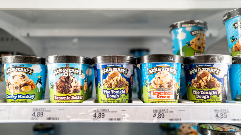 Ben & Jerry's pints sit on a shelf in a grocery store frozen section.