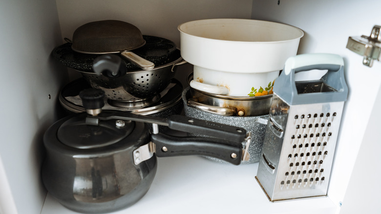 Kitchen cabinet with pots, pans, and utensils