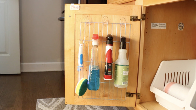 cleaning products hanging from wire rack inside cabinet door