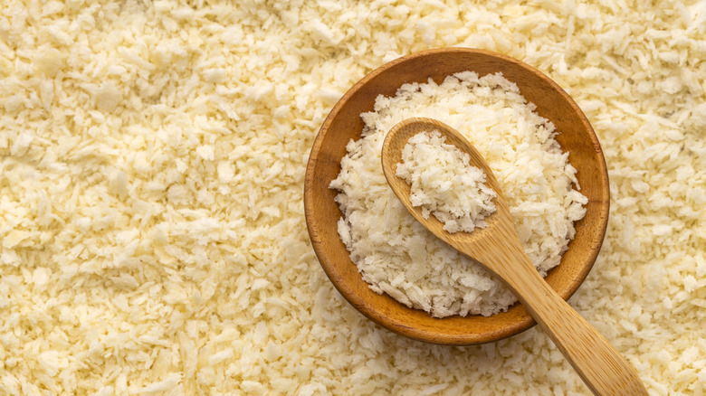 A small bowl of panko breadcrumbs and spoon surrounded by more panko