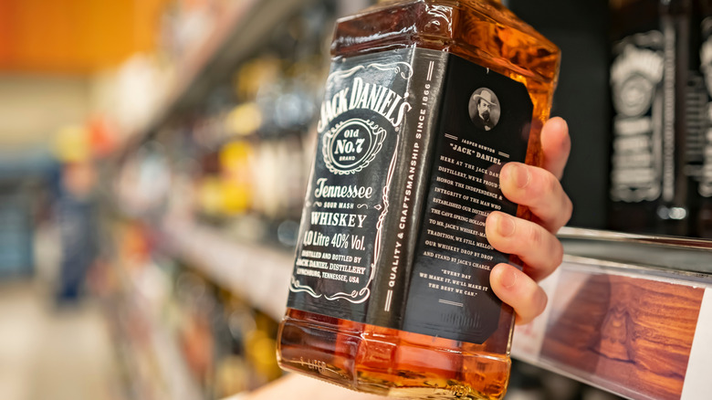 Ruka bere láhev Jacka Daniela z police