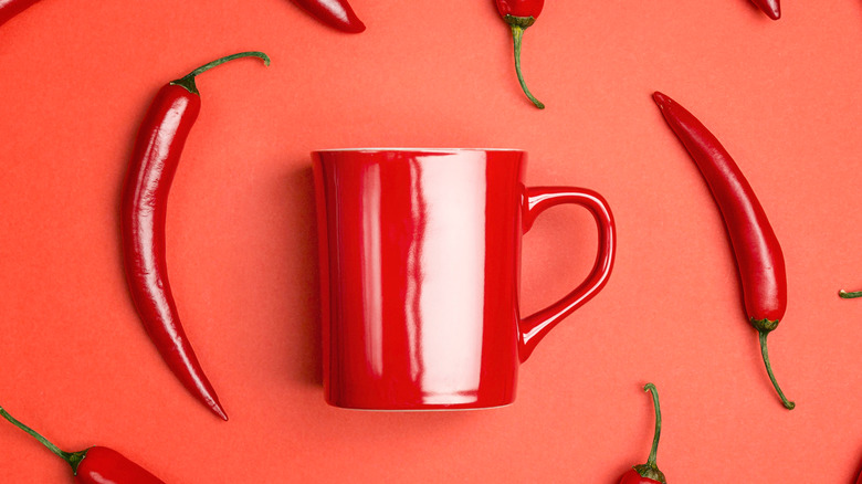 Red coffee cup surrounded by peppers