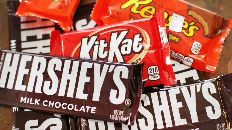various Hershey's products in a pile: milk chocolate bars, kit kats, reese's