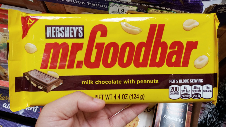 a hand holding up a Mr. Goodbar package in a store
