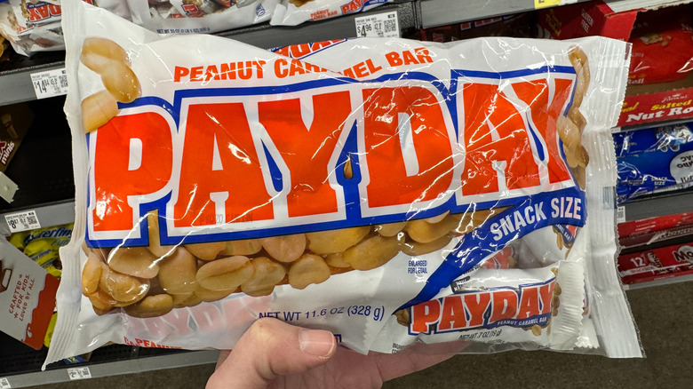 a hand holding up a Payday package in a store