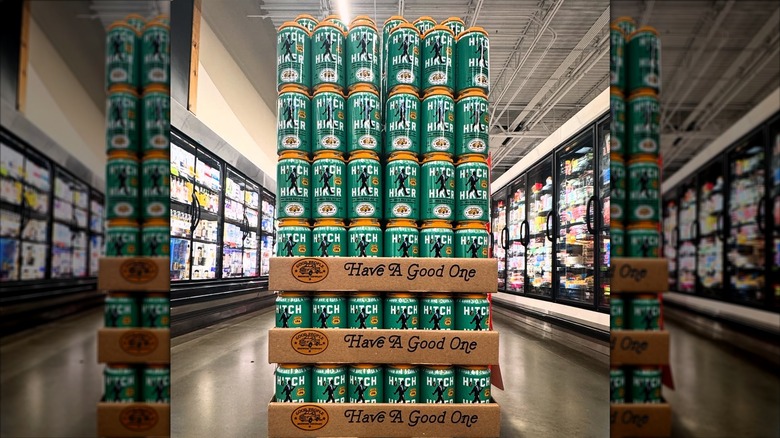 Stacked green cans of Hitchhiker IPA in a grocery store aisle