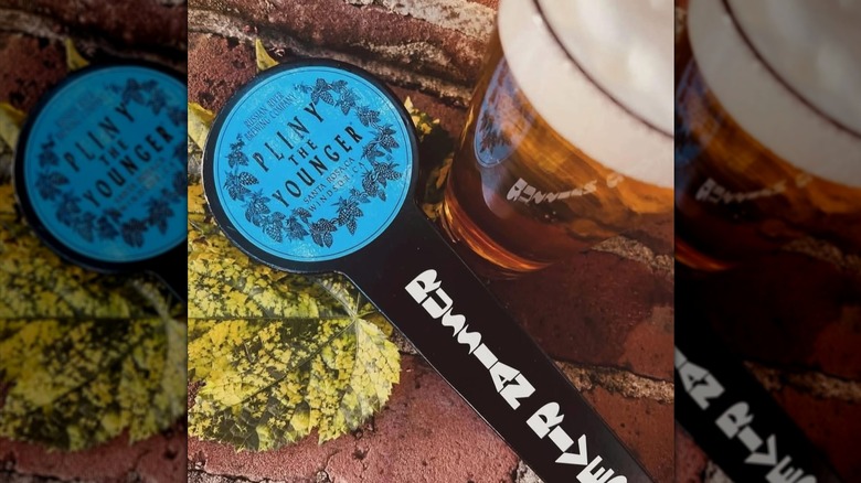 Pliny the Younger tap handle next to a glass of beer.