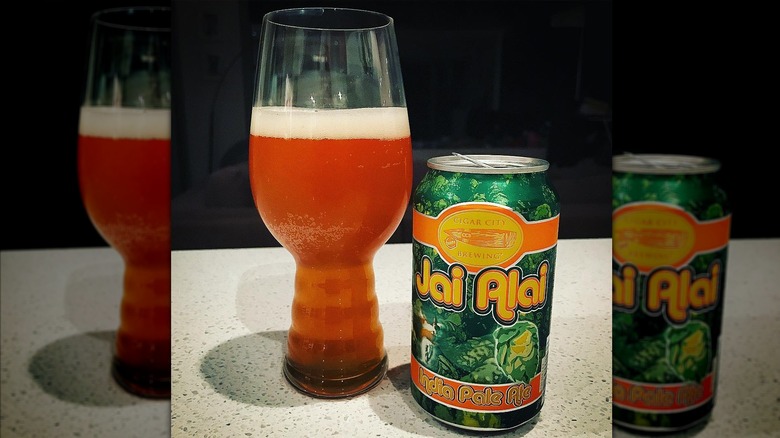 A glass of beer next to a can of Jai Alai IPA