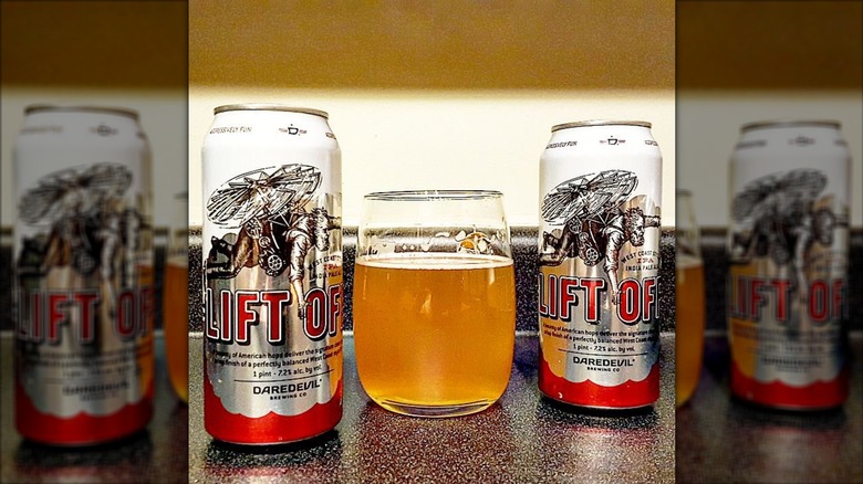 Two cans of Lift Off IPA flanking a beer-filled glass.