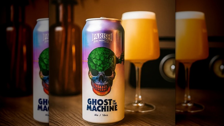 Ghost in the Machine IPA can in the foreground, a tall-stemmed glass filled with beer in the background.