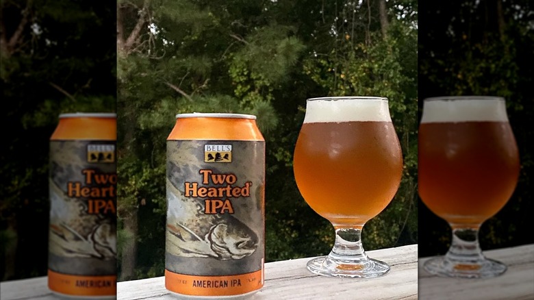 A can of Two Hearted IPA along with a full glass on a wooden porch railing.