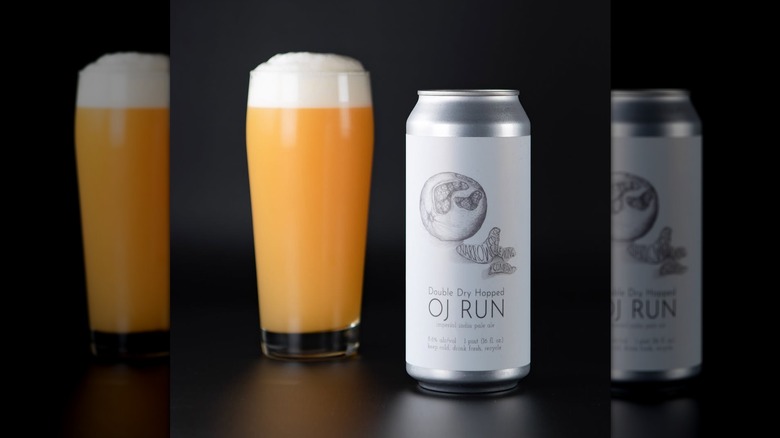 A black and white can of OJ Runn next to a filled beer glass.