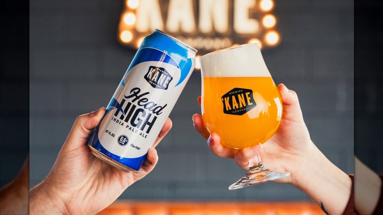 A can and a filled glass of Head High IPA toasting.