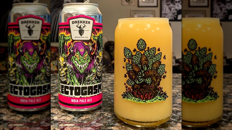 A filled to the brim glass with a picture of a monster hand crushing a handful of hops beside a can of Ectogasm IPA
