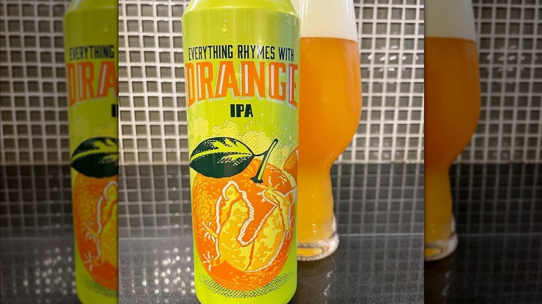 A can of Everything Rhymes wit Orange IPA in front of a full glass of beer.
