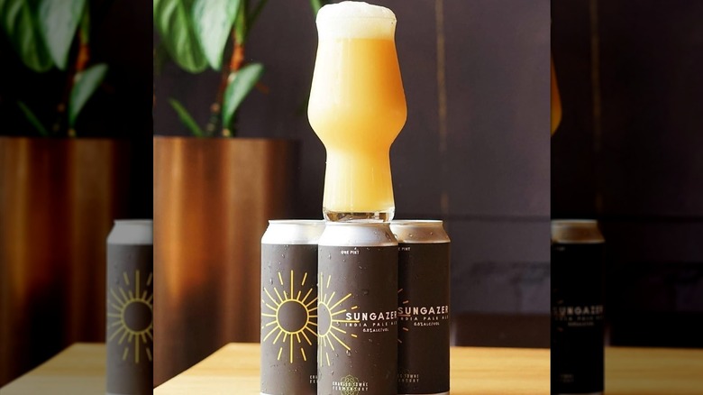 A filled pint glass on a pyramid of Sungazer IPA cans