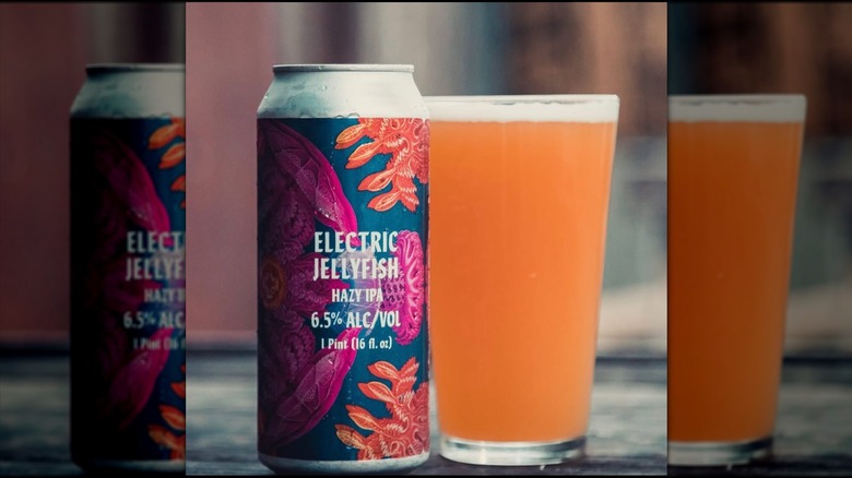 Purple, orange and blue can of Electric Jellyfish IPA next to a full pint glass.