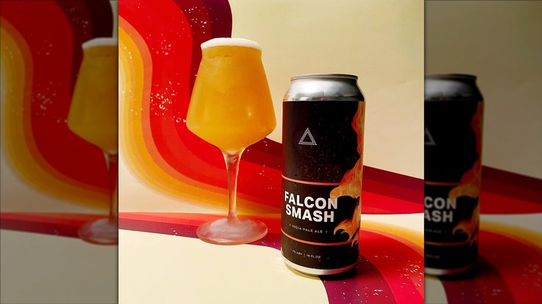 Black can of Falcon Smash IPA next to a filled long-stemmed beer glass