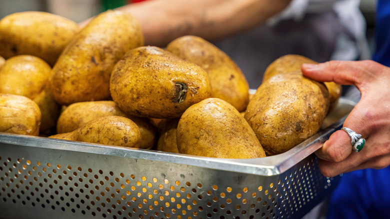 close up of woman holding tray full of potatoes